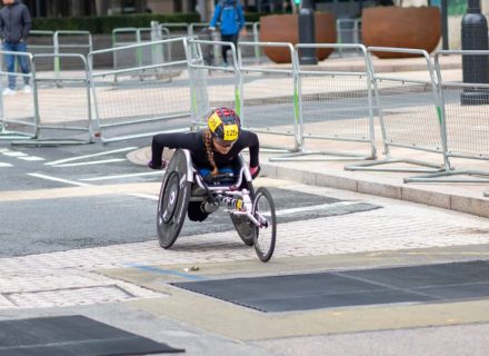 A dedicated athlete competes in a marathon using a racing wheelchair on city streets.