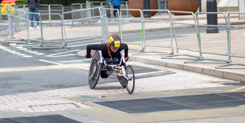 A dedicated athlete competes in a marathon using a racing wheelchair on city streets.